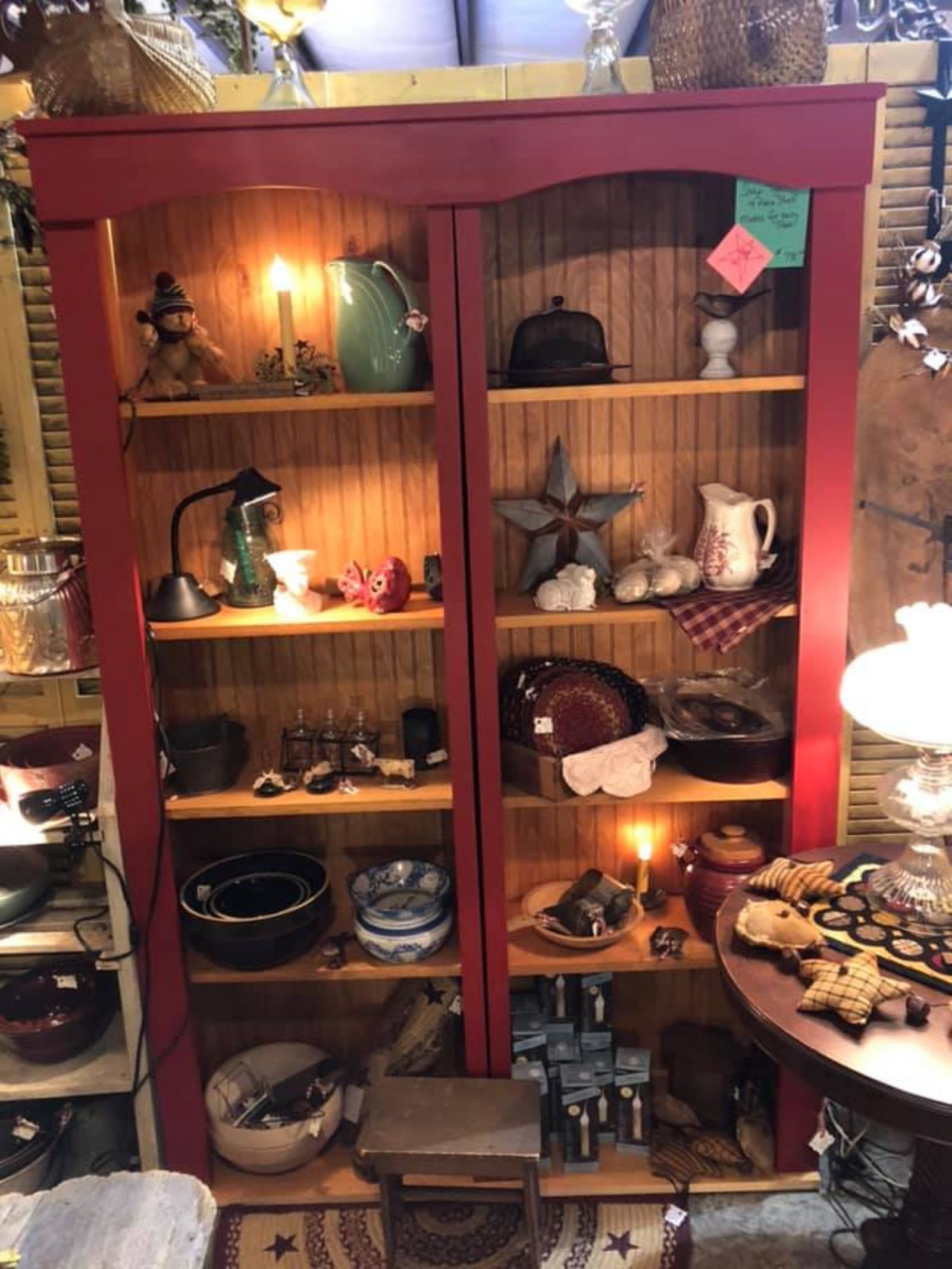 Warmly lit red cabinet displaying vintage pottery and antiques at Rocking Horse Antique Gallery